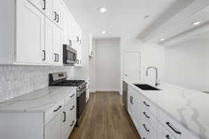 Kitchen with white cabinetry, light stone countertops, sink, and appliances with stainless steel finishes