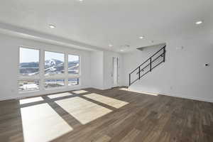 Unfurnished living room with a textured ceiling and dark wood-type flooring