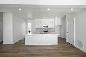 Kitchen with a center island with sink, dark hardwood / wood-style flooring, white cabinetry, and appliances with stainless steel finishes