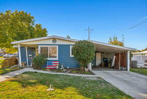 View of front of property featuring a carport and a front yard