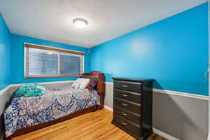 Bedroom with light hardwood / wood-style floors and a textured ceiling