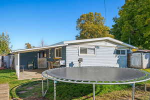 Back of property featuring a patio area, a lawn, and a trampoline