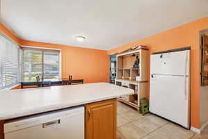 Kitchen with light tile patterned floors and white appliances