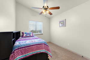 Bedroom featuring vaulted ceiling, carpet flooring, and ceiling fan