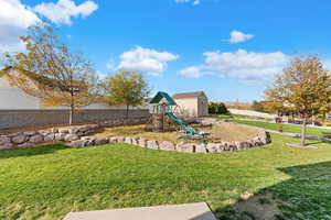 View of yard with a playground and a shed