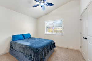 Bedroom featuring a closet, vaulted ceiling, light carpet, and ceiling fan