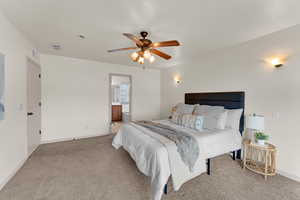 Carpeted bedroom featuring connected bathroom and ceiling fan