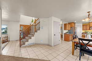 Kitchen with light tile patterned flooring, a textured ceiling, and an inviting chandelier