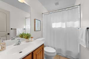 Full bathroom featuring vanity, shower / bath combo with shower curtain, tile patterned floors, and toilet