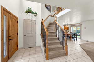 Foyer featuring a textured ceiling, a notable chandelier, and light tile patterned flooring