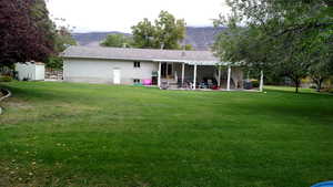 Back of property with a patio area, a lawn, and a mountain view