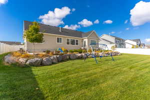 Rear view of property featuring a playground and a yard