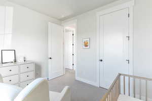 Bedroom with light colored carpet and a crib