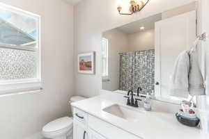 Bathroom featuring toilet, vanity, and plenty of natural light