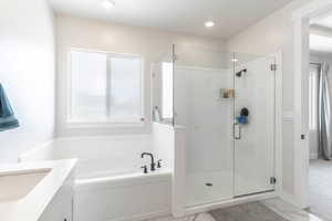 Bathroom featuring vanity and separate shower and tub