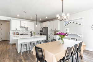 Dining room featuring dark wood-type flooring, a textured ceiling, sink, and an inviting chandelier