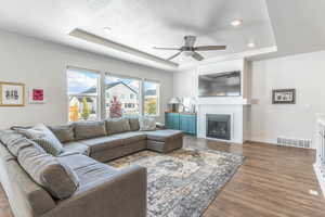 Living room with dark hardwood / wood-style flooring, a tray ceiling, a textured ceiling, and ceiling fan