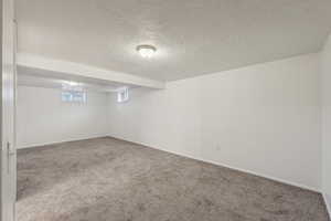 Basement featuring a textured ceiling and carpet floors