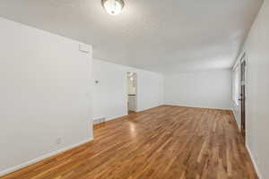 Empty room featuring a textured ceiling and hardwood / wood-style flooring