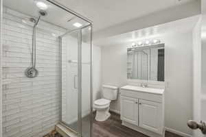 Bathroom with walk in shower, vanity, hardwood / wood-style floors, and toilet