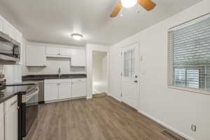 Kitchen with sink, appliances with stainless steel finishes, light hardwood / wood-style flooring, white cabinets, and decorative backsplash