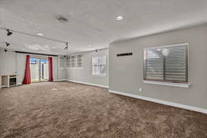 Spare room featuring a textured ceiling, carpet floors, and plenty of natural light