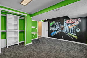 Recreation room with a textured ceiling and dark carpet