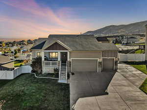 View of front of property with a lawn, a mountain view, and a garage