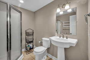 Bathroom with toilet, tile patterned floors, and a shower with shower door