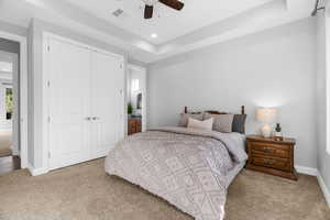 Bedroom featuring light colored carpet, ceiling fan, connected bathroom, and a closet