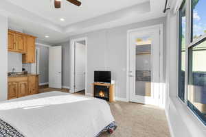 Carpeted bedroom featuring access to outside, sink, connected bathroom, ceiling fan, and a raised ceiling