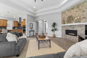 Living room featuring a fireplace, light carpet, and ceiling fan