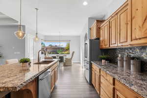 Kitchen featuring a center island with sink, decorative backsplash, sink, dark hardwood / wood-style floors, and appliances with stainless steel finishes