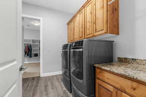 Laundry area with washer and clothes dryer, dark wood-type flooring, and cabinets