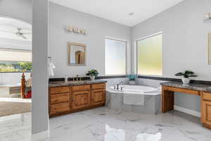 Bathroom featuring vanity, tiled bath, and ceiling fan