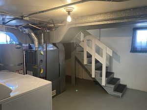 Basement featuring strapped water heater and washer / dryer