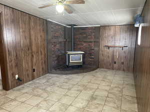 Family room featuring ceiling fan, wooden walls, and a Gas stove