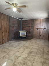 Family room with wooden walls, a Gas stove, and ceiling fan