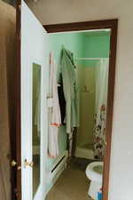 Bathroom featuring curtained shower, a textured ceiling, and toilet