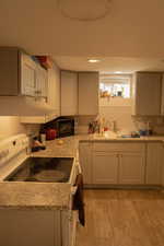 Kitchen with decorative backsplash, light hardwood / wood-style flooring, sink, and electric stove