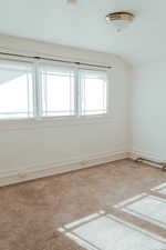 Carpeted spare room with vaulted ceiling