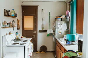 Kitchen with white electric stove, carpet, and stainless steel fridge