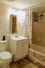 Full bathroom featuring toilet, vanity, shower / bath combination with curtain, and hardwood / wood-style floors