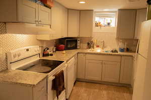 Kitchen featuring decorative backsplash, light hardwood / wood-style flooring, sink, and white appliances