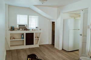 Interior space featuring cooling unit, vaulted ceiling, and light hardwood / wood-style floors