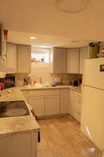 Kitchen featuring tasteful backsplash, white refrigerator, sink, and light hardwood / wood-style flooring