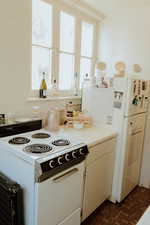 Kitchen featuring backsplash, white electric range, and white cabinets