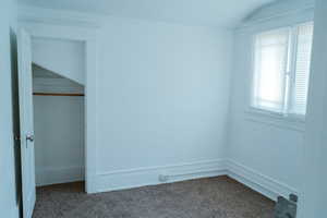 Unfurnished bedroom featuring a closet, lofted ceiling, and carpet flooring