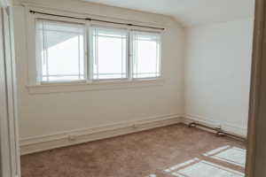 Carpeted empty room with vaulted ceiling