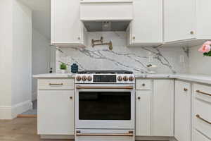 Cafe gas range with full quartz backsplash, brass pit filler, and custom cabinets